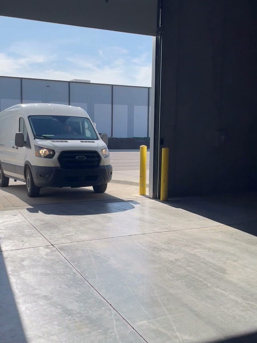 A delivery van backing into the covered drive-in bay